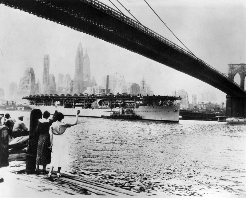 Citizens wave as the Langley passes under the Brooklyn Bridge